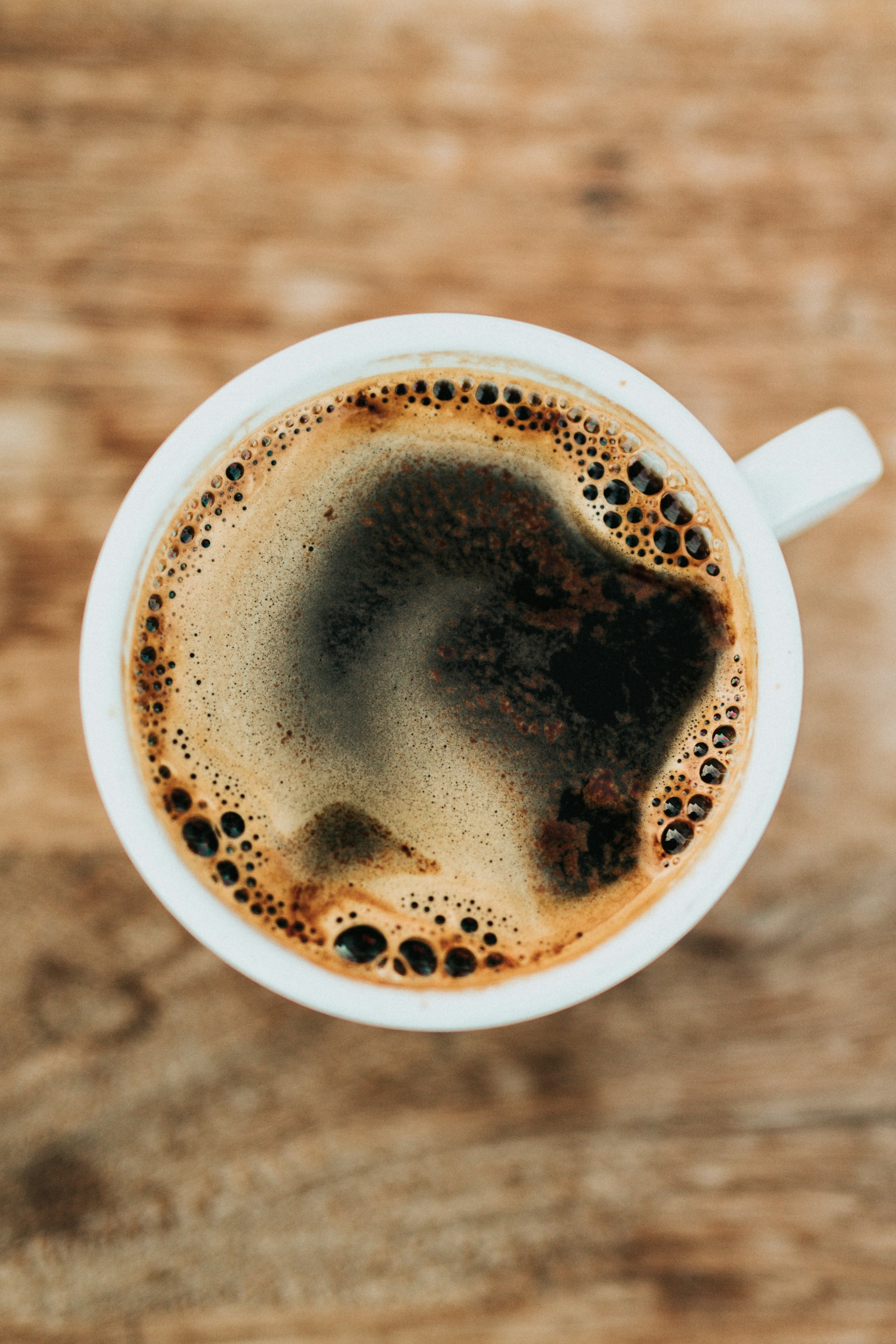 Close up of espresso pouring into a ceramic cup from a professional espresso machine, cinematic lighting, warm beige and chocolate tones, no people
